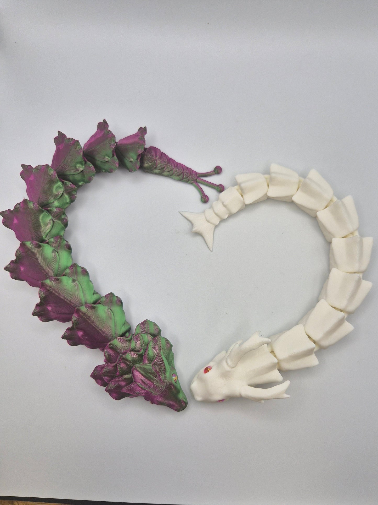 Two 3D printed articulated dragons in a heart shape