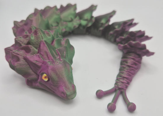 Green and purple 3D-printed articulated dragon on a white background