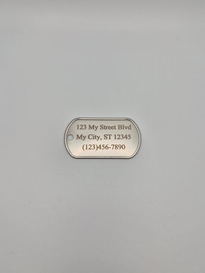 Aluminum, military ID-style dog tag with  full street address & phone number sitting on a gray background