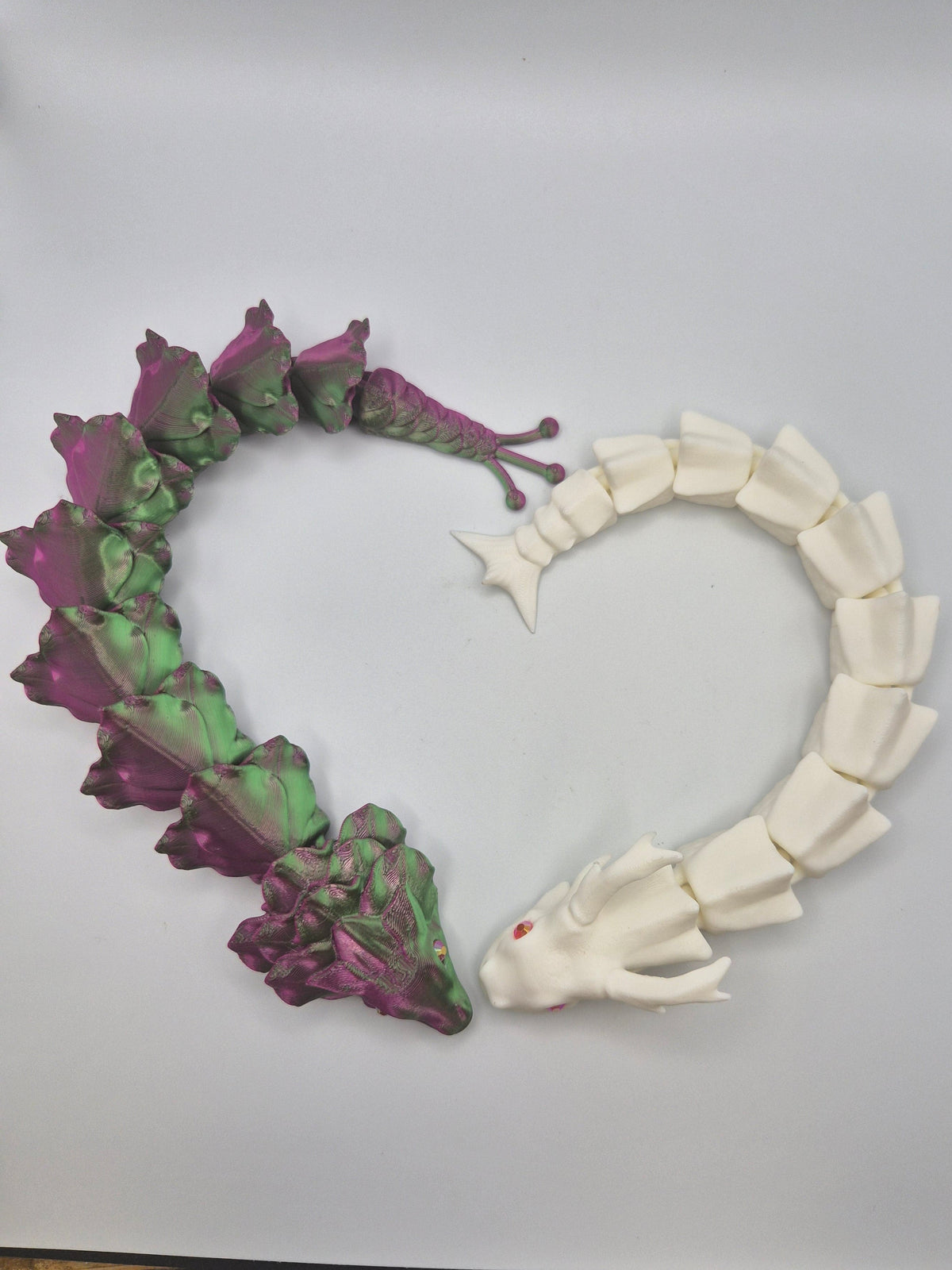 Two 3D printed articulated dragons in a heart shape