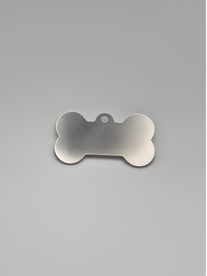 Stainless steel bone-shaped dog tag on a light background