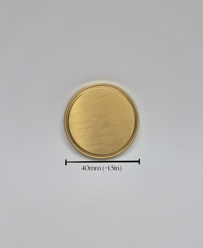 A round brushed brass or gold-colored metal disc shown on a light gray background, with a black measurement line and text below indicating a diameter of 40mm (-1.5in).