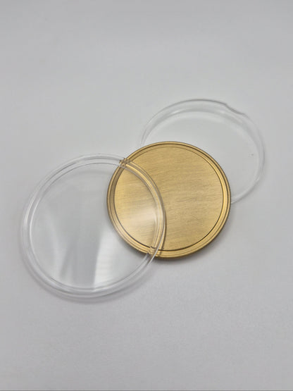 Gold, blank commemorative coin with clear plastic protective cover open on a light background