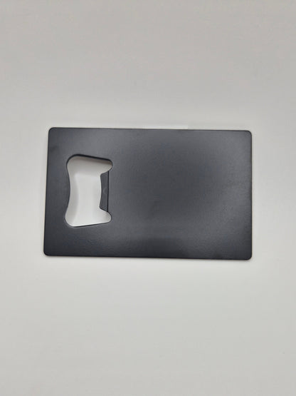 Credit card-sized, stainless steel bottle opener with a matte black finish on a light background