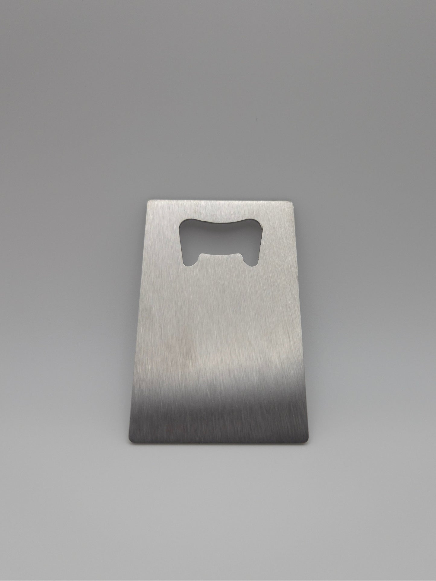 Brushed stainless steel, credit card-sized bottle opener on a light background