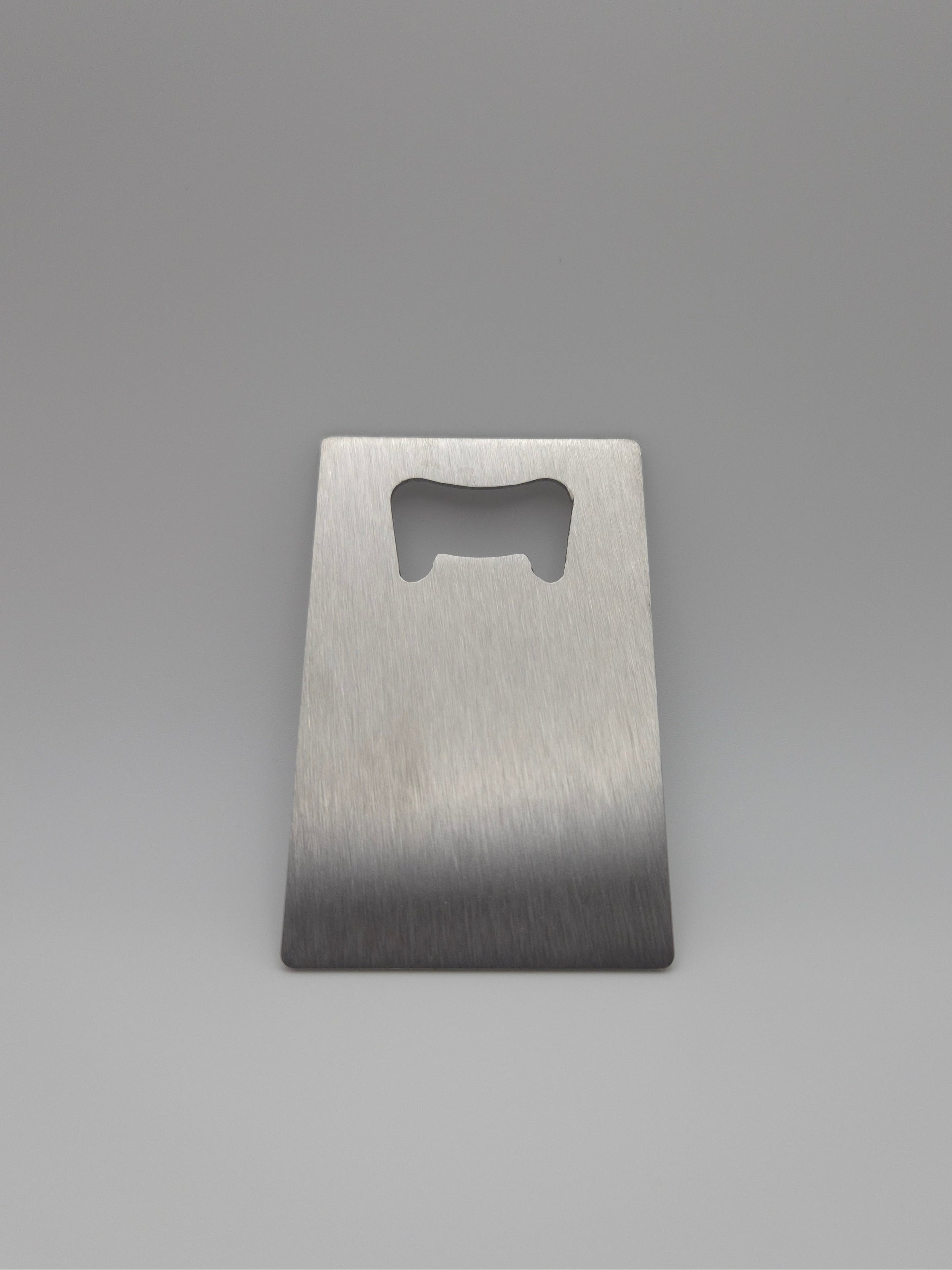 Brushed stainless steel, credit card-sized bottle opener on a light background