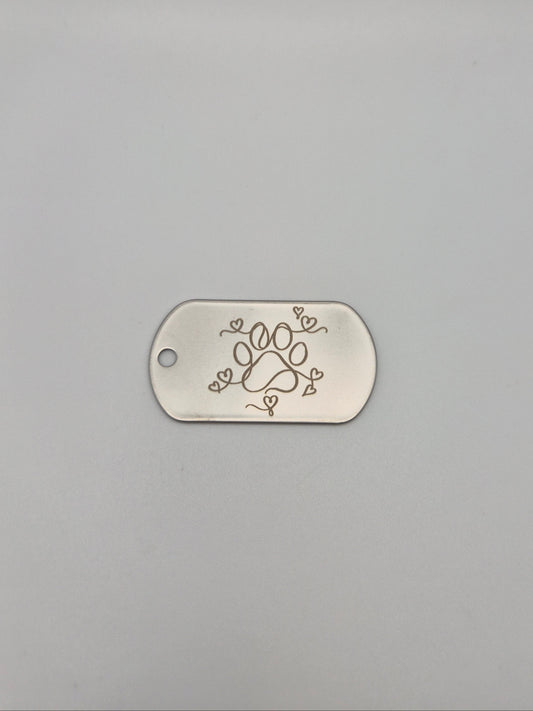 Aluminum, military ID-style dog tag with engraved paw & hearts design on a gray background