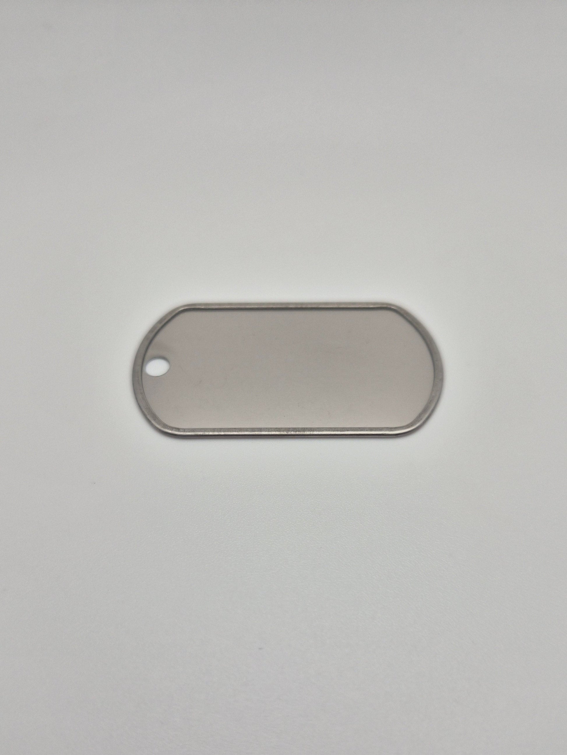 Back side, with a rolled edge, of an aluminum, military id-style dog tag on a light background