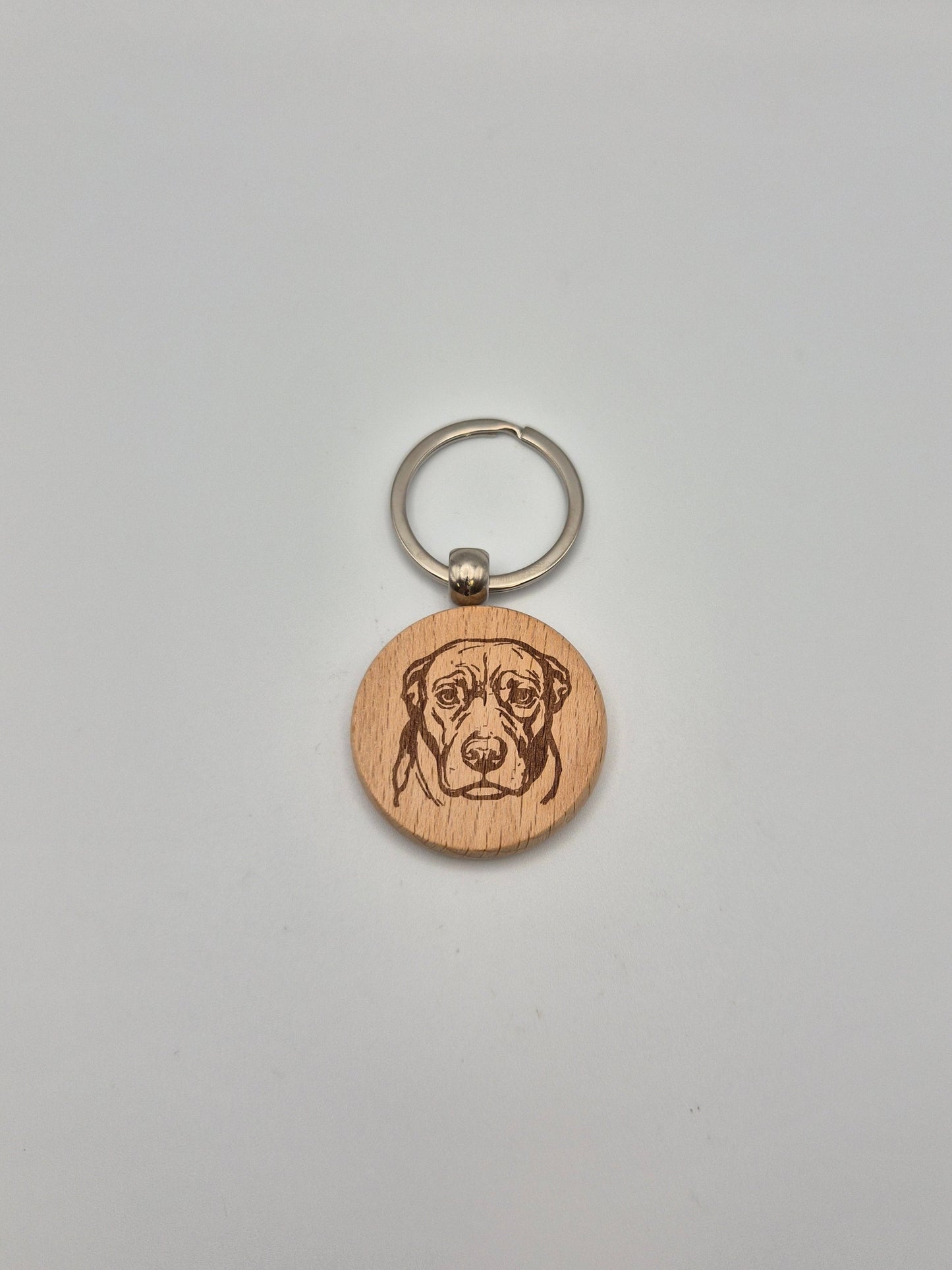 Wooden keychain with engraved dog face on a gray background