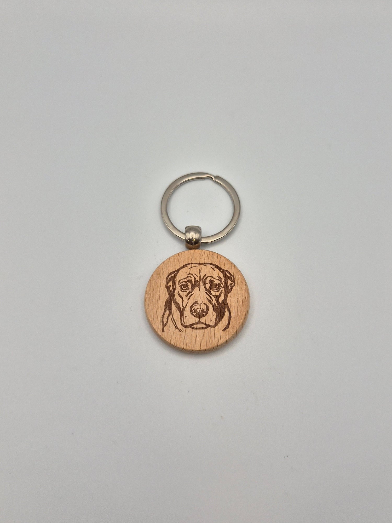 Wooden keychain with engraved dog face on a gray background