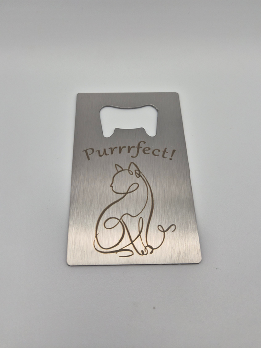 Brushed, stainless steel, credit card-sized bottle opener with an engraved single-line-drawing-style cat design and the text 'Purrfect!' sitting on a light background