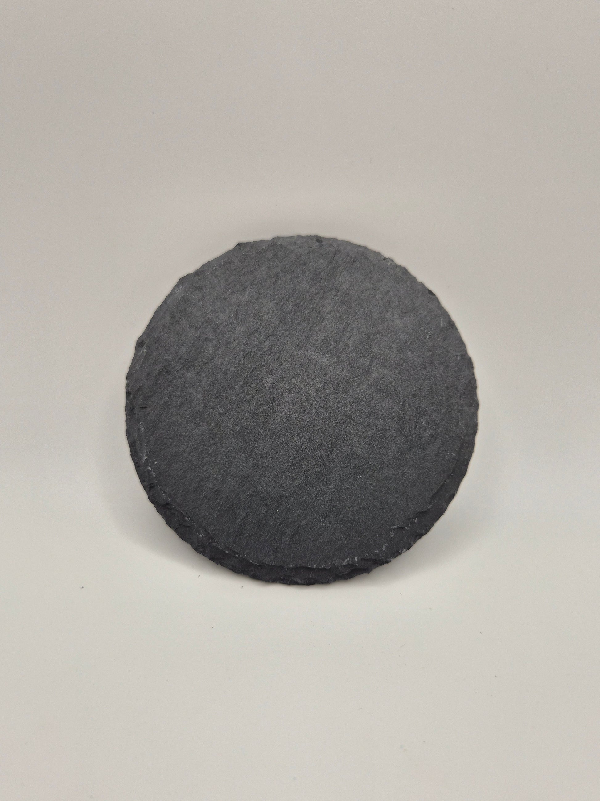One round, gray slate coaster on a light background