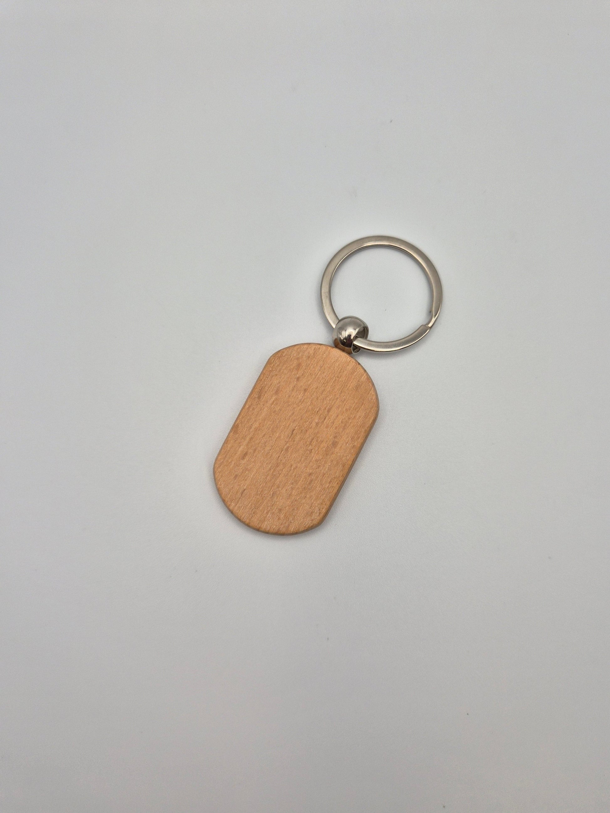 Oval, wooden keychain with metal ring sitting on a light gray background