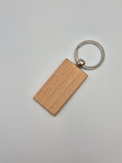 Rectangular, wooden keychain with metal ring sitting on a light gray background