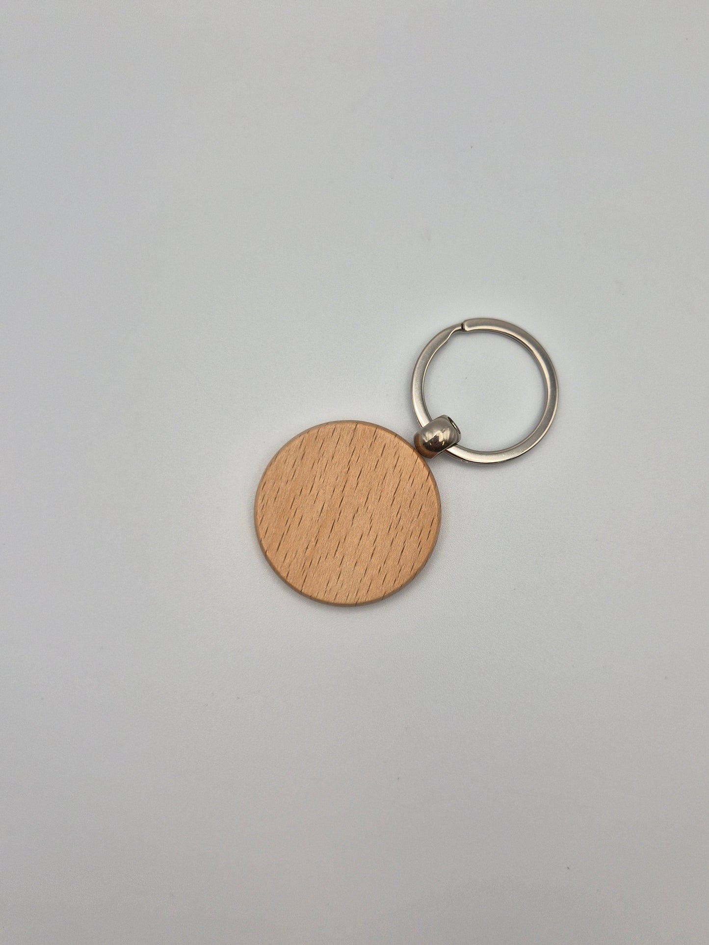 Round, wooden keychain with metal ring sitting on a light gray background