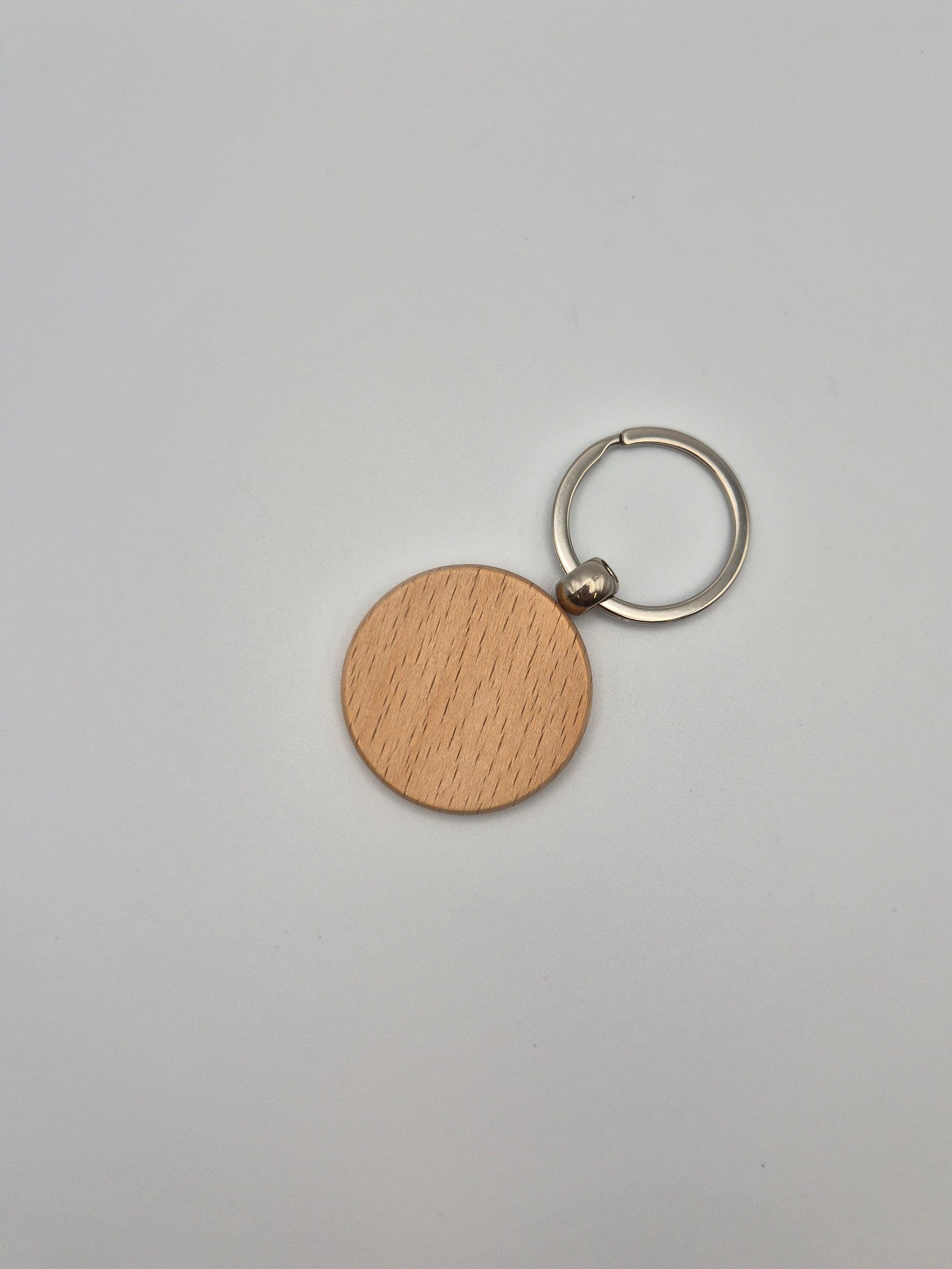 Round, wooden keychain with metal ring sitting on a light gray background